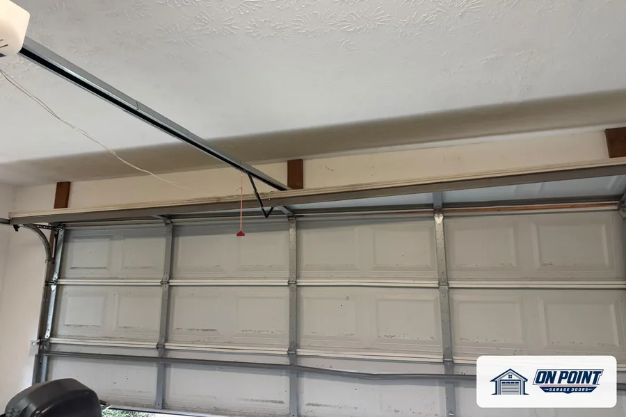 Sectional garage door seen from inside, with its tracks and opener arm